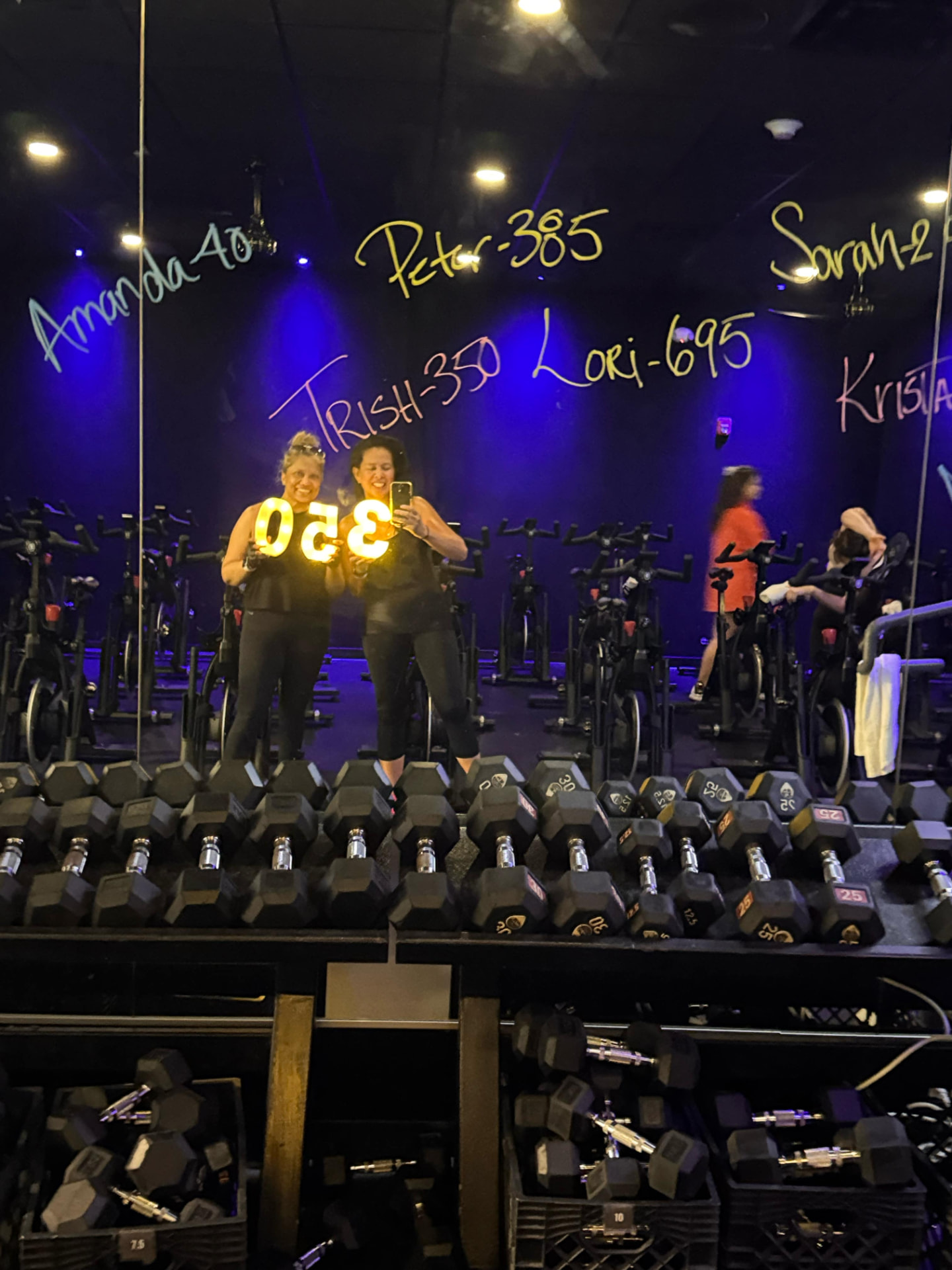 Two members holding a lit 350 in the cycling theater